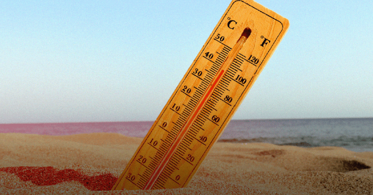 Um termômetro no chão de areia, simbolizando onda de calor